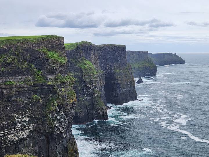 Dramatic view of the Cliffs of Moher plunging into the Atlantic with waves crashing below.
