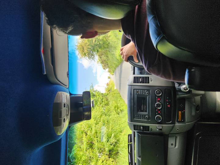 Passenger-eye view from inside a tour van driving down a narrow Irish country lane.