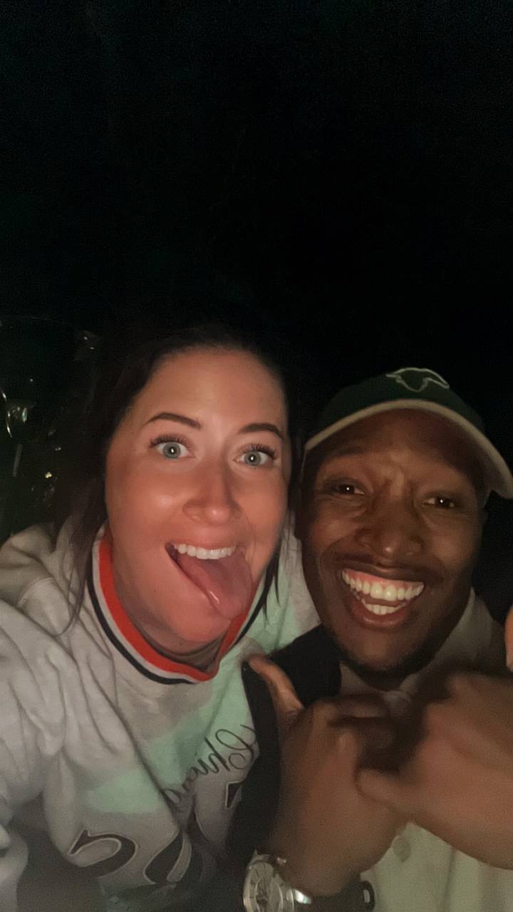 Close-up nighttime selfie of two friends laughing in dim light