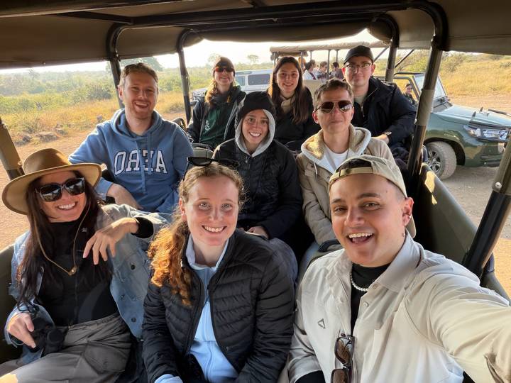 Safari participants smile inside an open 4x4 vehicle ready for a game drive on a sunny morning.