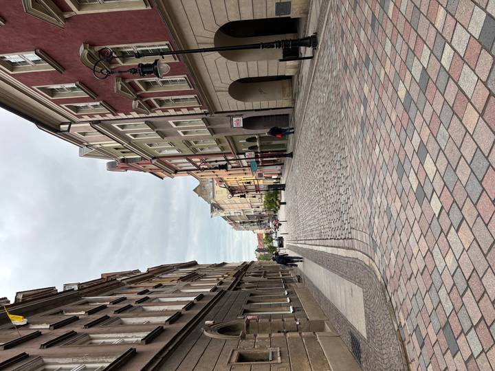 Quiet cobblestone street lined with colorful townhouses under a gray sky in a Polish old town.
