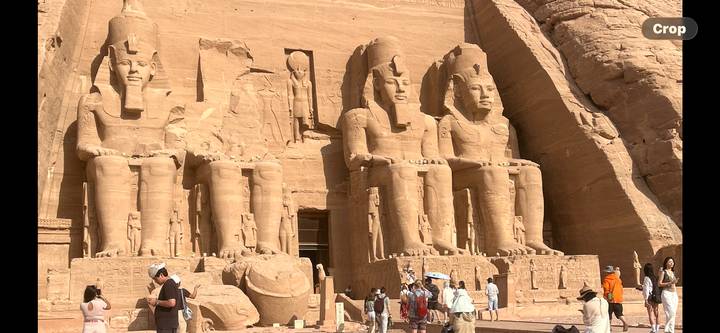 Wide view of Abu Simbel’s colossal statues with clusters of tourists exploring the forecourt.