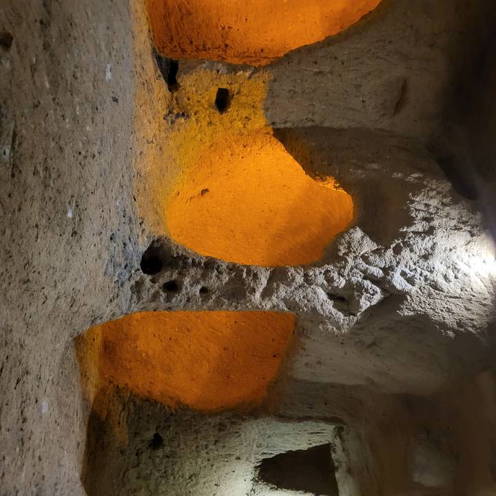 Orange-lit chambers carved into soft rock inside a Cappadocian cave.