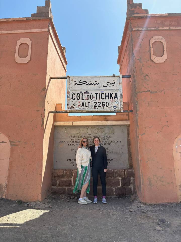 Two travelers pose beneath the altitude sign at the Tizi n'Tichka mountain pass.
