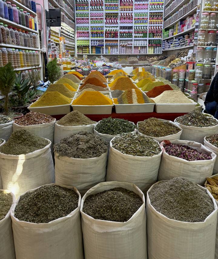 Colorful mounds of spices neatly displayed in sacks at a Moroccan market.