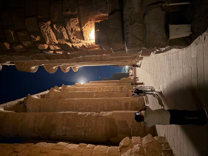 Moonlit colonnade of Karnak Temple with towering sandstone pillars at night.