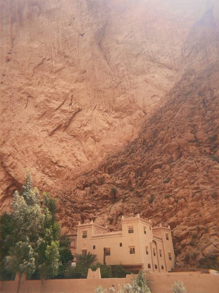 Textured red rock cliff face likely from a Moroccan gorge.