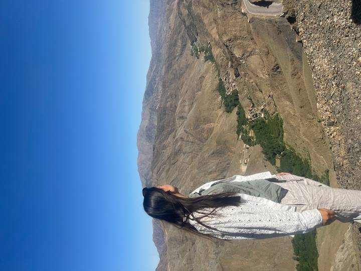 Woman looks out over rugged Atlas Mountains and scattered villages below.