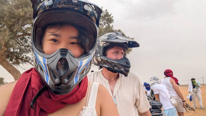 Travelers wear protective helmets and scarves ready for a desert quad adventure.