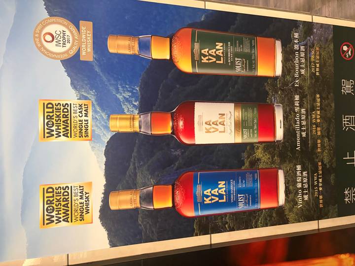 Advertising poster showcasing three bottles of Kavalan whisky with award badges.