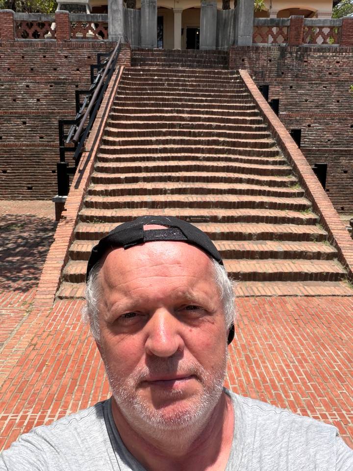 Selfie cropping a man’s forehead with historic red-brick steps ascending behind him.
