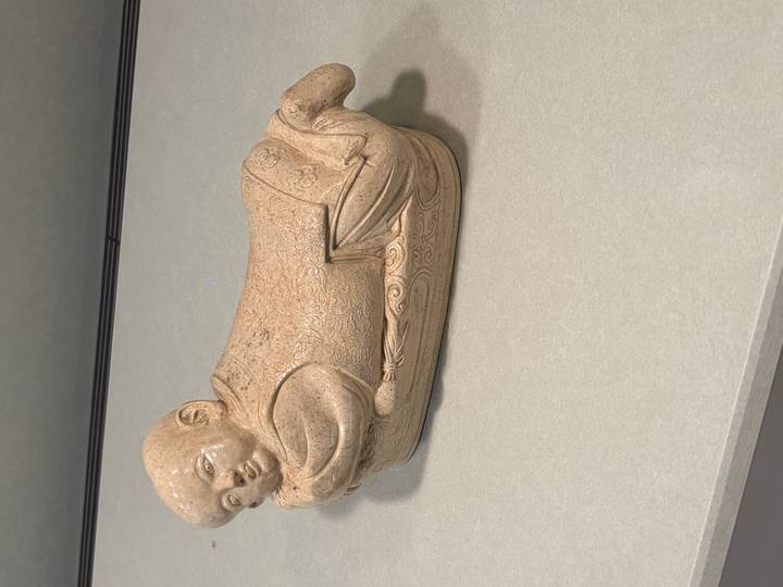 A beige ceramic reclining child figure displayed on a countertop.