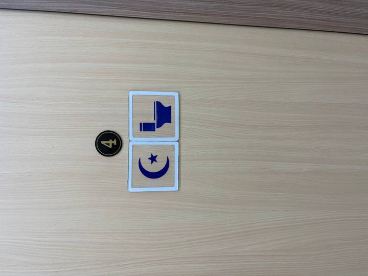 Minimalist door sign combining a crescent-star symbol and toilet icon under the number 4.