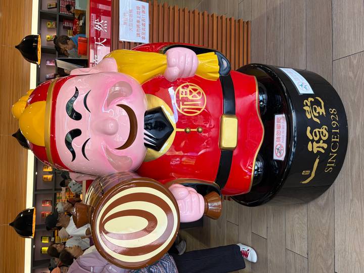 Colourful smiling figurine of a lucky god holding a mallet inside a shop.
