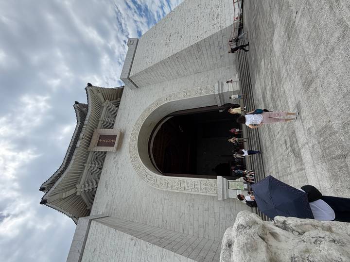 Wide shot of the imposing main arch and entrance of the Chiang Kai-shek Memorial Hall with visitors below.