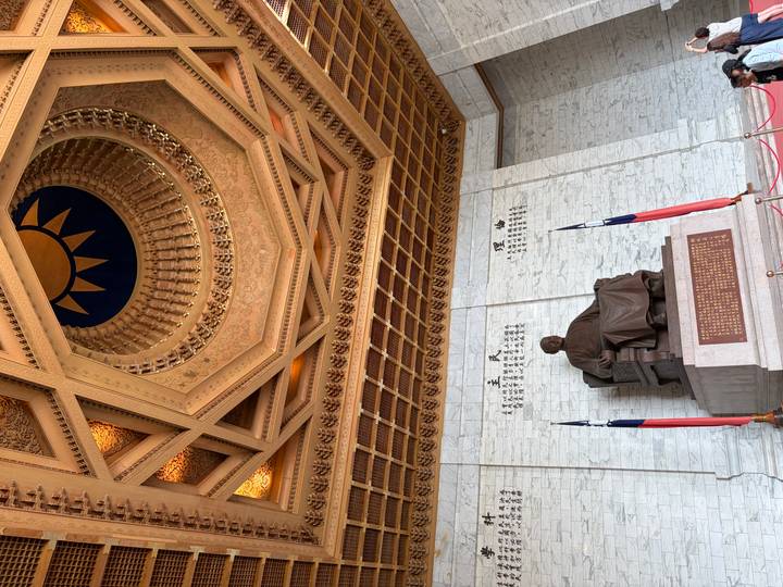 Interior of the Chiang Kai-shek Memorial featuring the seated bronze statue below an ornate coffered ceiling.
