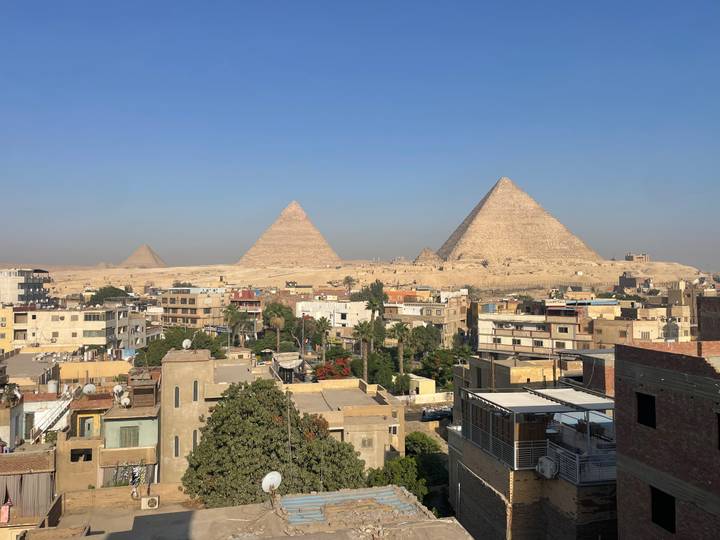 Panoramic rooftop view of Cairo’s urban sprawl with the three main pyramids rising beyond the city.