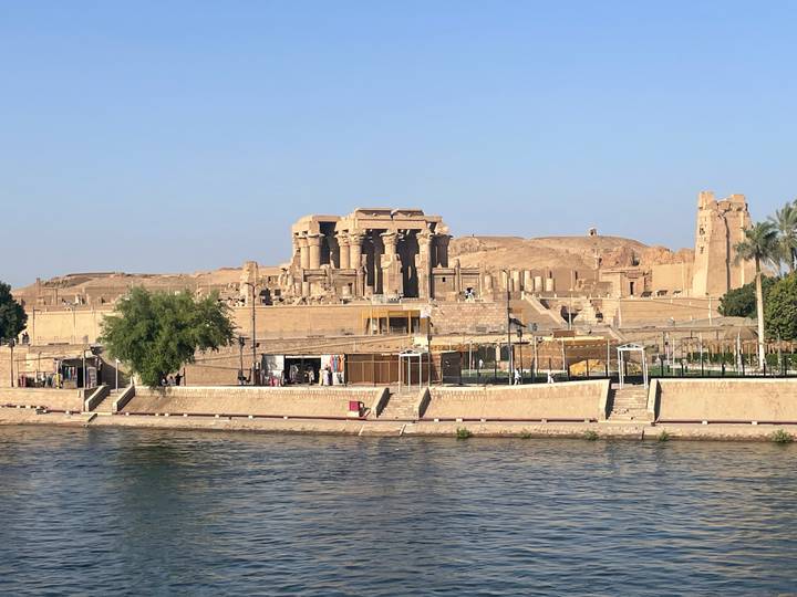 Kom Ombo Temple complex seen from across the Nile with sandy hills rising behind the ruins.