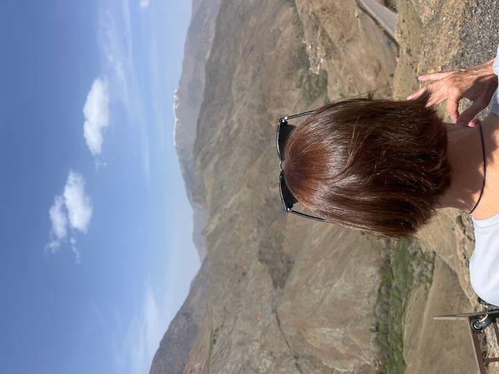 Back view of a woman looking out over rugged Atlas Mountains with snow-capped peak in the distance.