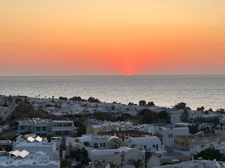 Afterglow of sunset fading over the sea and white houses of a Santorini village.