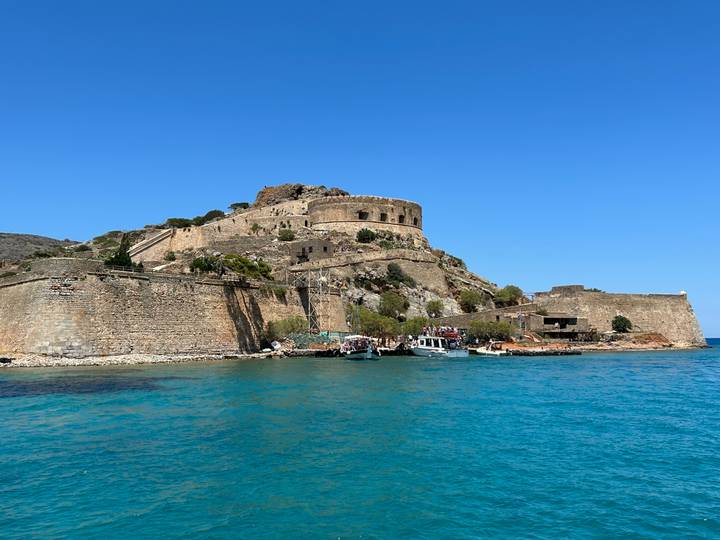 Stone fortress of Spinalonga Island rising above turquoise waters.
