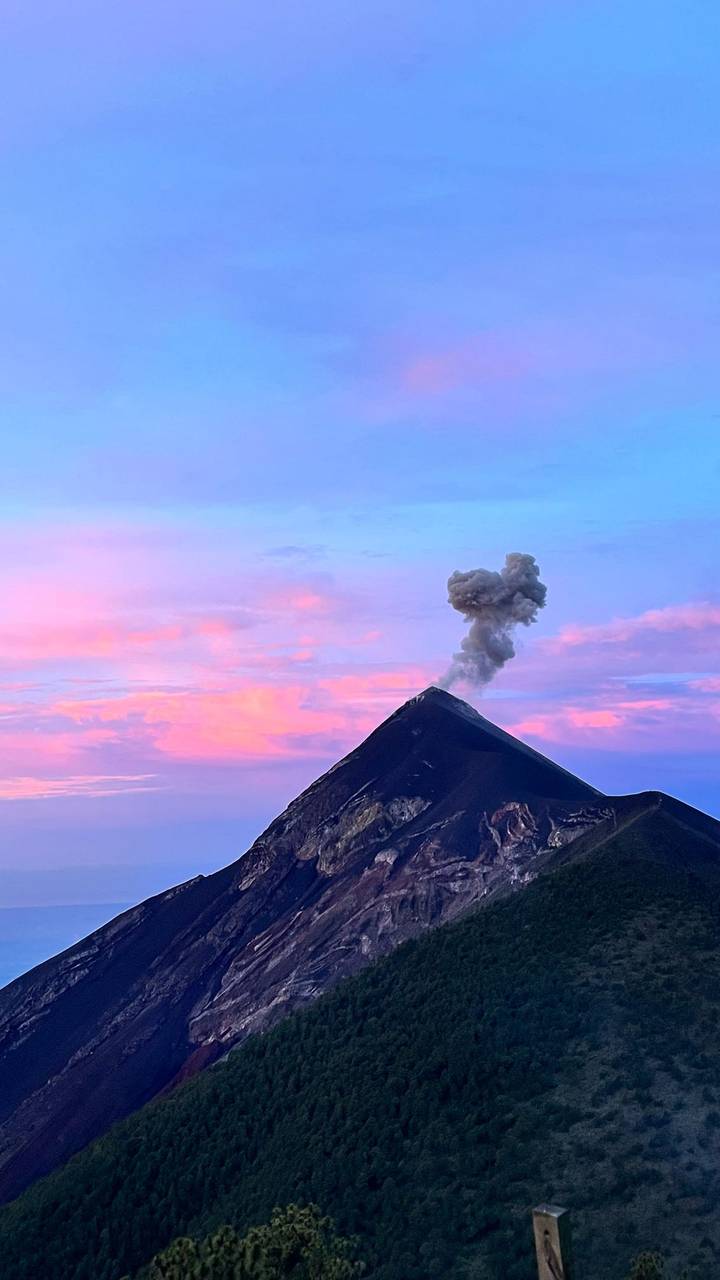 Smoking cone of an active volcano against pastel sunset sky