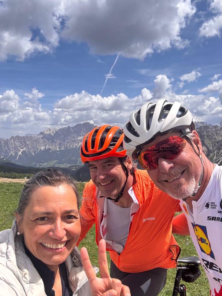 Cyclists taking selfie with dramatic alpine mountain backdrop under bright sky