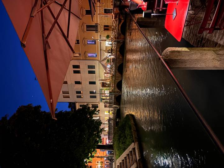 Evening canal scene with lit restaurants and stone bridge in historic town