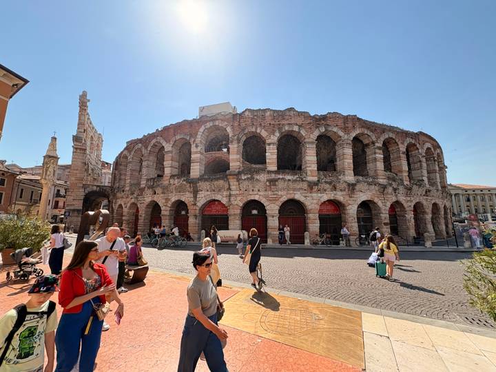 Busy daytime scene at Verona Arena with tourists walking and cycling