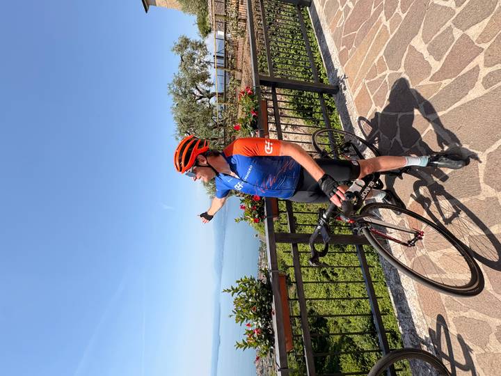 Cyclist pointing over Lake Garda from scenic balcony viewpoint