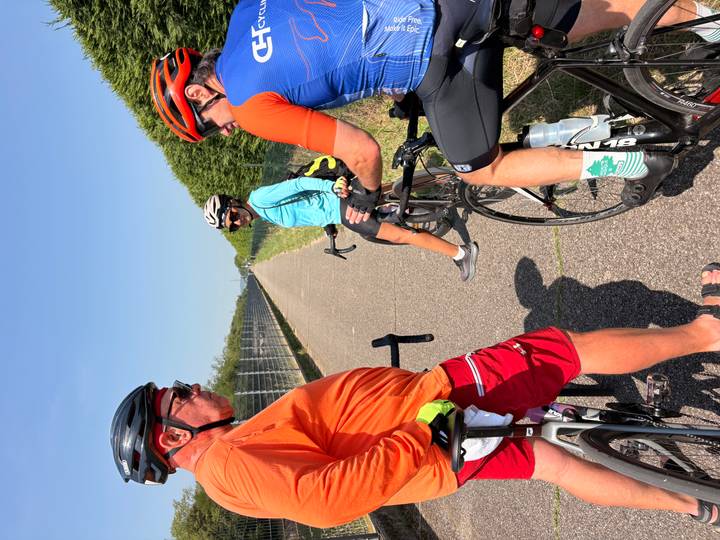 Cyclists stopped on long straight bike path under clear blue sky