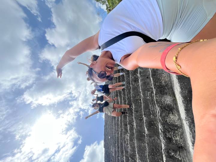 Energetic selfie of women joyfully climbing ancient pyramid steps under bright sky