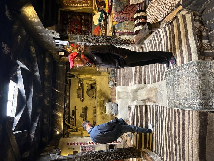 Travellers explore a traditional interior filled with striped carpets and rustic décor.