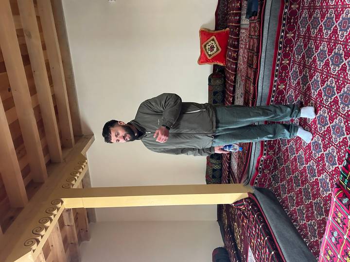 Guide speaks to visitors inside a carpeted room, gesturing with one hand.