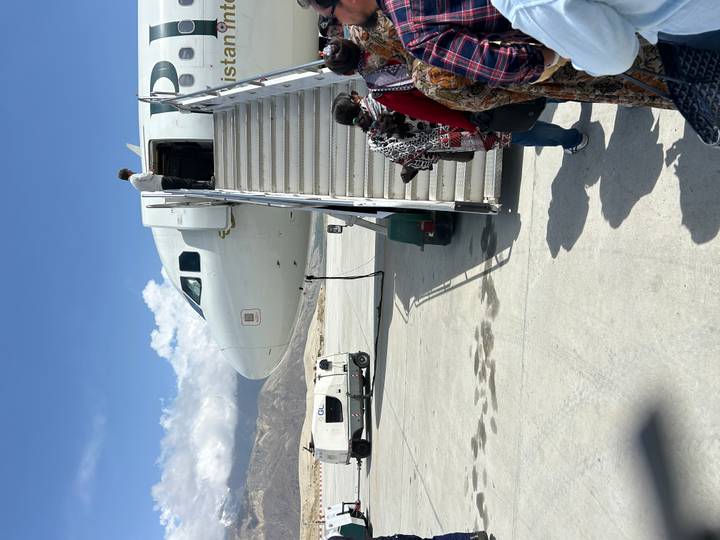Passengers board a small commercial aircraft via mobile stairs on a sunny tarmac.