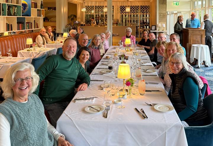 Dinner gathering of travellers seated around a long white-clothed table in a restaurant.