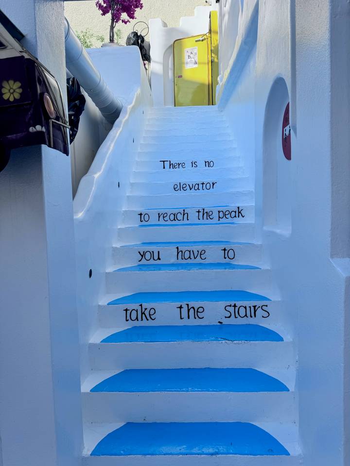 Whitewashed staircase with blue accents bearing inspirational words encouraging visitors to take the stairs.