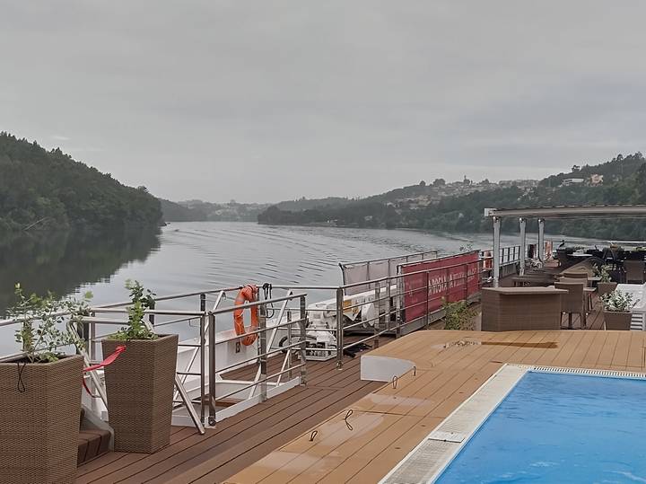 River cruise ship deck with pool on a calm misty morning cruising through a forested valley.