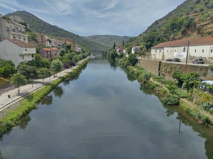 Narrow river canyon lined with pastel villages and green slopes stretching toward distant bridges.