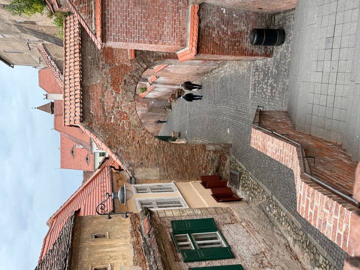 Cobblestone alleyway with a brick arch and three pedestrians strolling in an old town setting.