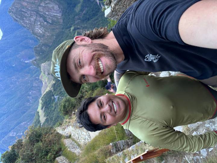 Traveller and local guide smiling on a steep stone trail in lush mountains