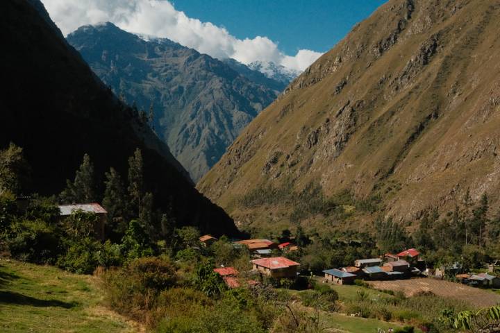 Small Andean village with red-roofed houses nestled between steep green mountains