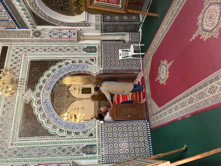 Ornate tiled entrance of a Moroccan mosque with worshippers entering