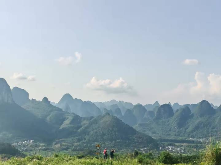 Hazy vista of karst mountains layered in soft blue tones stretching into the distance.
