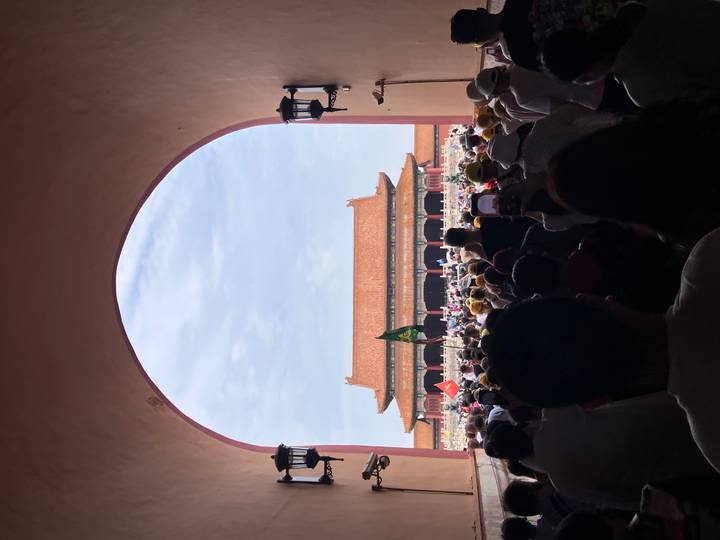Crowds stream through an arched gate toward the Forbidden City’s main hall under a sunny sky.