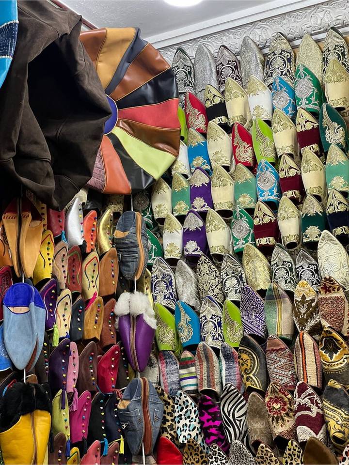 Colourful wall display of embroidered Moroccan leather slippers in assorted patterns and hues.