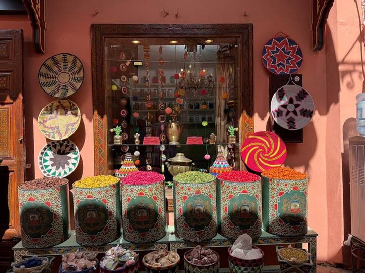 Colourful front display of spice barrels and woven baskets outside a Marrakech shop.