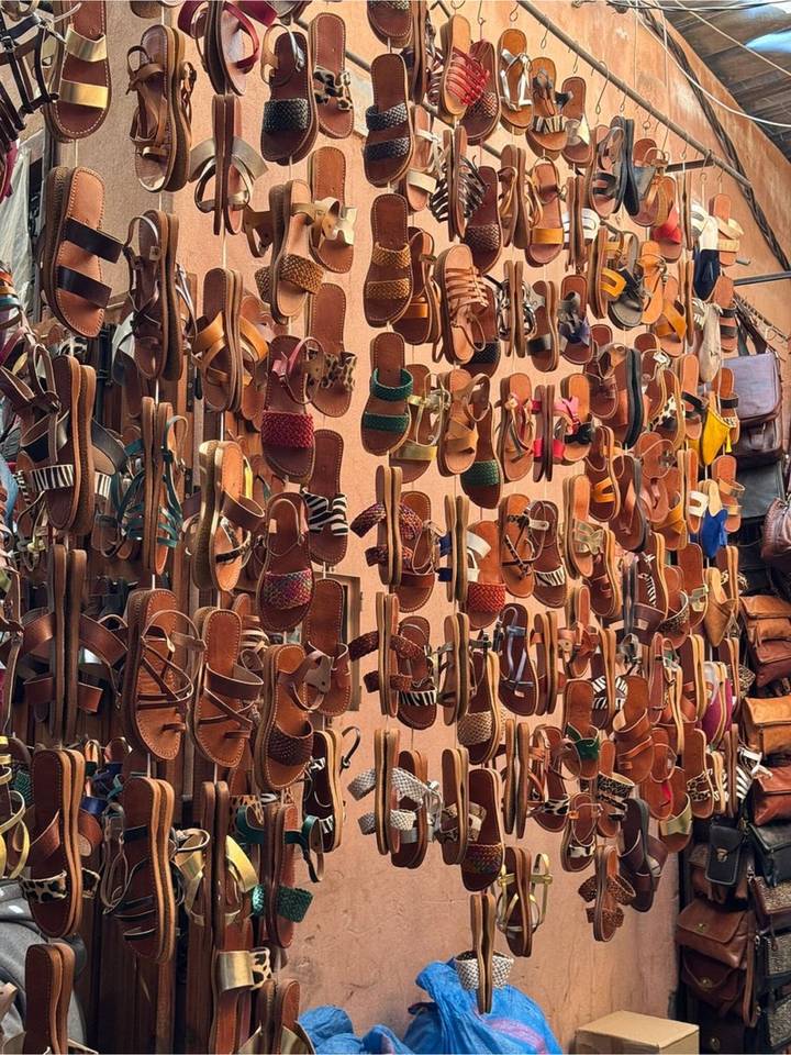 Rows of hanging handcrafted leather sandals in various designs at a Marrakech market stall.