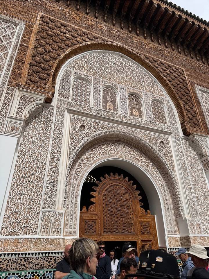 Close detail of ornate carved and inlaid archway with complex geometric patterns on a Moroccan building.