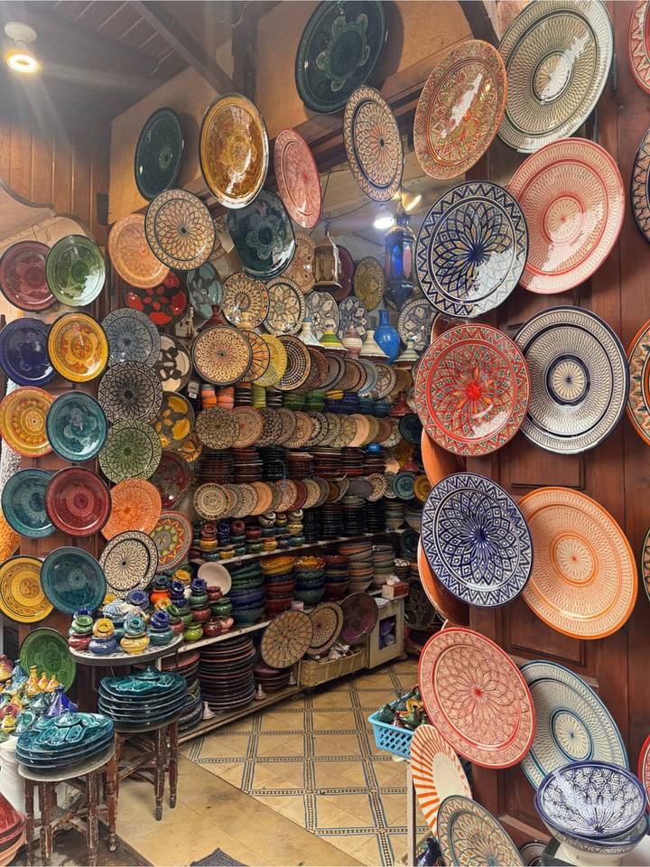 Vibrant shop display of stacked and hanging hand-painted Moroccan ceramic plates in every colour.